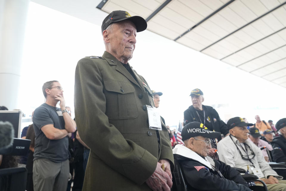 World War II veteran Bob Hartline stands and listens to a speaker before boarding a plane with other veterans at Dallas Fort Worth International Airport in Dallas, Friday, May 31, 2024. A group of World War II veterans are being flown from Texas to France where they will take part in ceremonies marking the 80th anniversary of D-Day. (AP Photo/LM Otero)