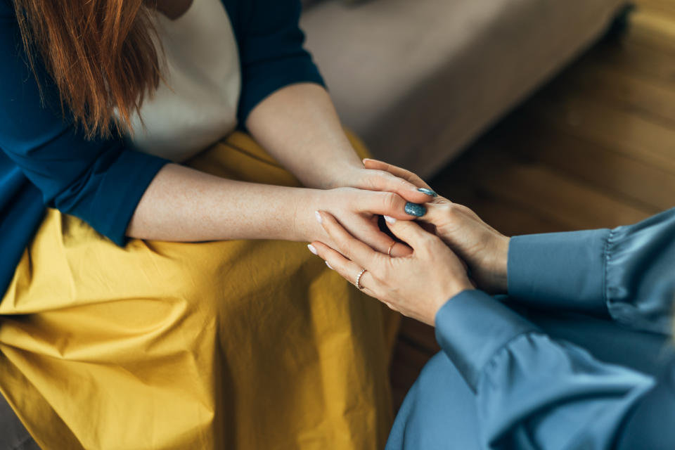 Two women sitting in armchairs and talking. Woman psychologist talking to patient woman. Coach giving hands to smiling woman. Therapist's gestures. Female talking in coworking office