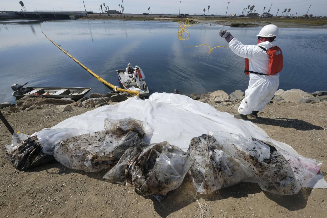 Cleanup contractors collect oil in plastic bags trying to stop further oil crude incursion into the Wetlands Talbert Marsh in Huntington Beach, Calif., Sunday, Oct. 3, 2021.