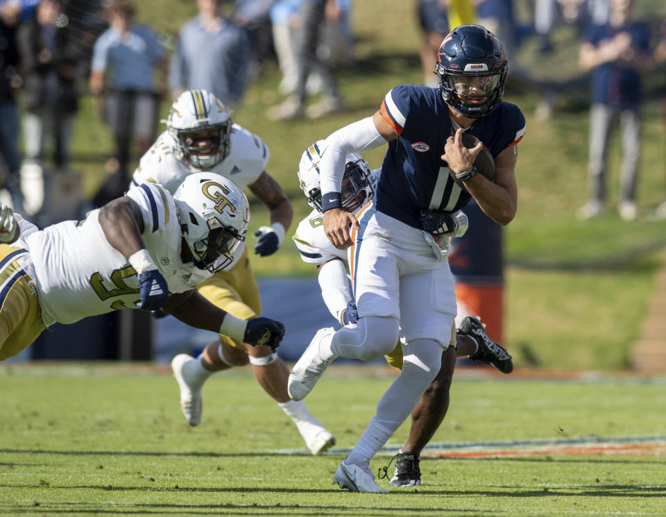 Virginia quarterback Tony Muskett (11) is tackled by Georgia Tech defensive lineman D'Quan Douse (99) and defensive back K.J. Wallace (16) during the first half of an NCAA college football game Saturday, Nov. 4, 2023, in Charlottesville, Va. (AP Photo/Mike Caudill)