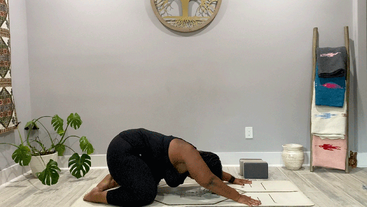 Woman on her knees on her yoga mat practicing a 15-minute slow flow in the pose known as Child's Pose