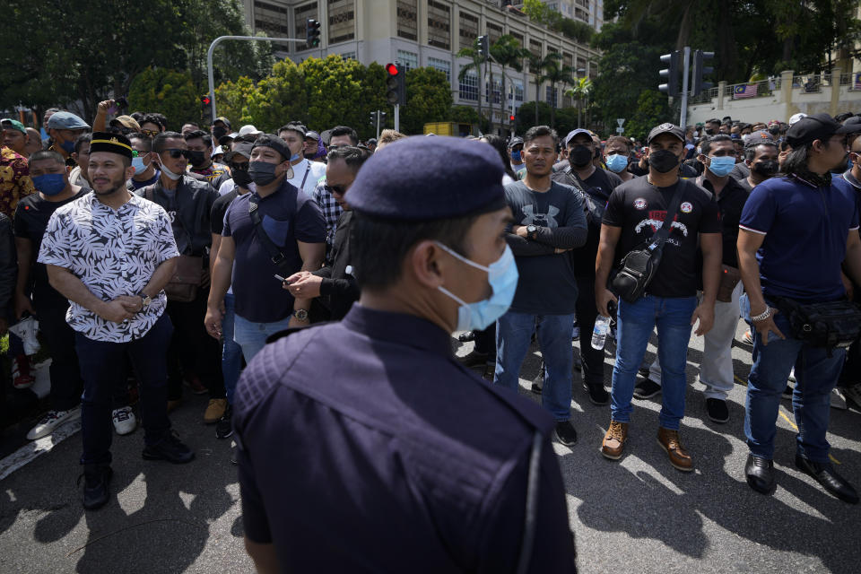 Police with riot shield stand guard as supporters of Malaysia's former Prime Minister Najib Razak gather outside the National Palace in Kuala Lumpur, Malaysia, Wednesday, Aug. 24, 2022. They gathered to seek royal intervention just a day after Najib began a 12-year jail term, while opponents launched an online petition urging the monarch to deny clemency. (AP Photo/Vincent Thian)