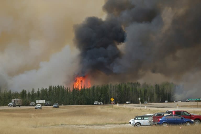 A convoy of evacuees drives south as flames and smoke rises along the highway near Fort McMurray in Alberta, Canada on May 6, 2016