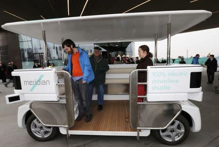 People stand on a prototype of a driverless vehicle as it is displayed to members of the media in Greenwich, east London, February 11, 2015. REUTERS/Suzanne Plunkett