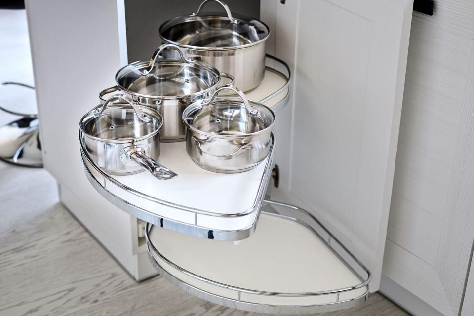 Silver pots and pans in corner storage of kitchen cabinets