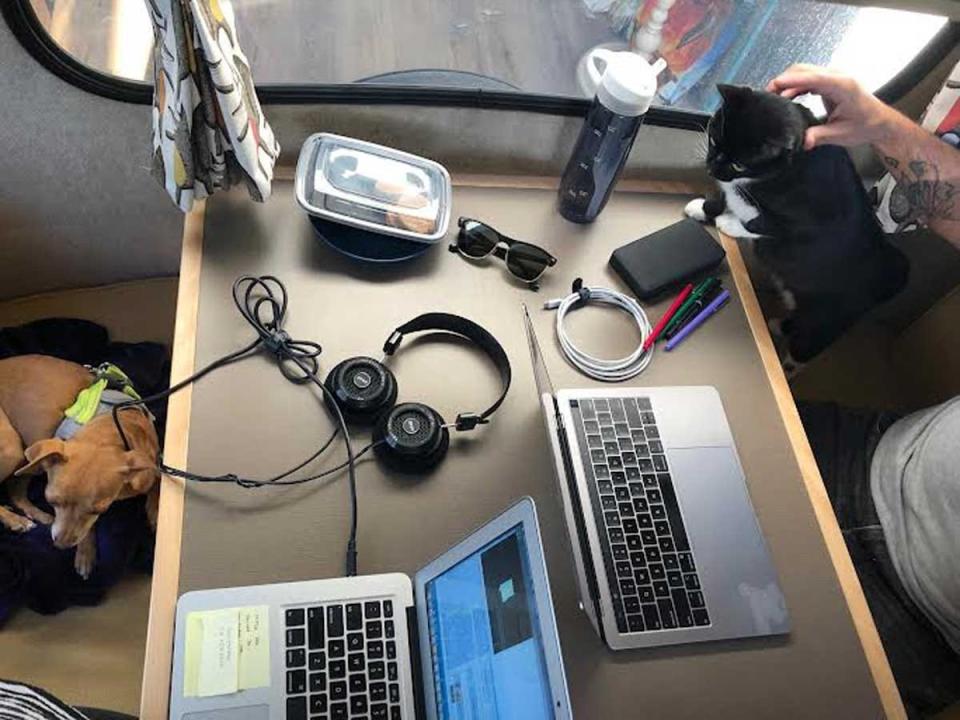 A table in a travel trailer with computers, pets, and meals.