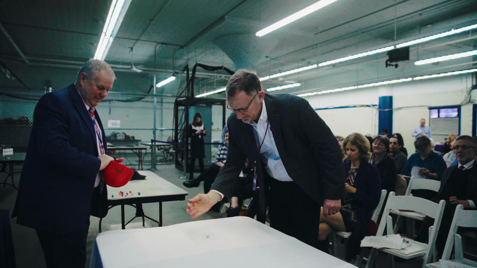 Robert Rapoza, executive director of the Rhode Island Board of Elections, and Mike Goetz of Election Systems & Software participate in the dice roll to kick off Rhode Island's pilot risk-limiting audit in Providence on Jan. 16. | Sky Sabin—Sky Sabin Productions, LLC