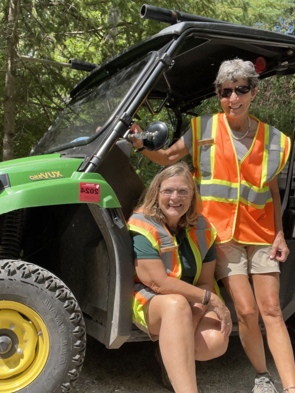 Nancy Gilliom, left, and Heidi Wasson stand outside the Gator Utility Vehicle they use to get around while cleaning campsites as volunteer camp hosts at Peninsula State Park in Fish Creek.