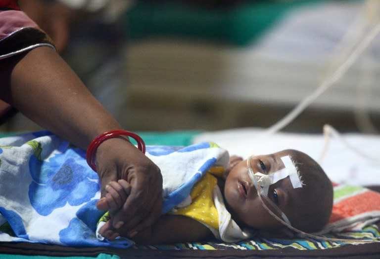 This file photo taken on August 14, 2017 shows an Indian woman holding her child's hand at the encephalitis ward of the Baba Raghav Das Hospital in Gorakhpur, in the northern Indian state of Uttar Pradesh