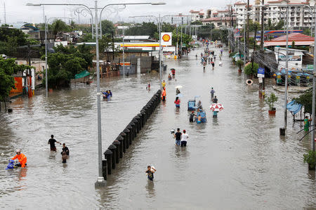 Residents wade and ride on pedicabs along a partially flooded road, in Las Pinas Metro Manila as a storm sweeps across the main Luzon island, Philippines, September 12, 2017. REUTERS/Erik De Castro