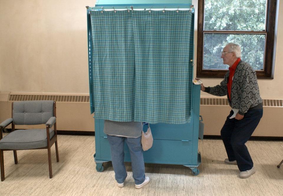 Election inspector Herb Derman checks voter numbers as Ginny Kennedy-Tette votes at Summerville Presbyterian Church in Irondequoit on Sept. 25, 2001.