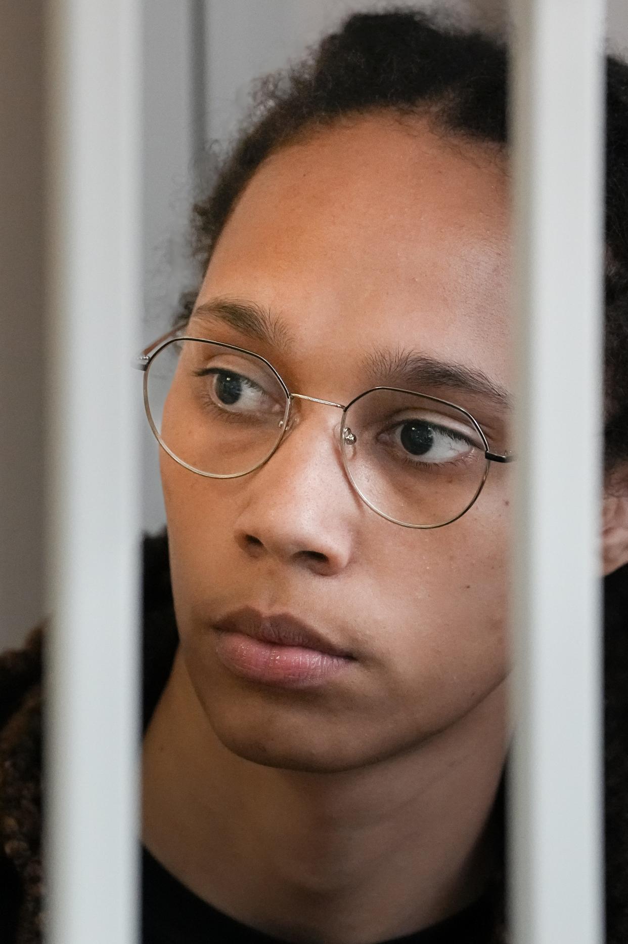 WNBA star and two-time Olympic gold medalist Brittney Griner looks through bars sitting in a cage in a courtroom prior to a hearing, in Khimki just outside Moscow, Russia, Wednesday, July 27, 2022.