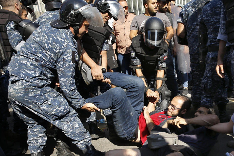 Anti-government protesters lie on a road and hold each others as riot police try to remove them and open the road, in Beirut, Lebanon, Thursday, Oct. 31, 2019. Army units and riot police took down barriers and tents set up in the middle of highways and major intersections Thursday. (AP Photo/Bilal Hussein)