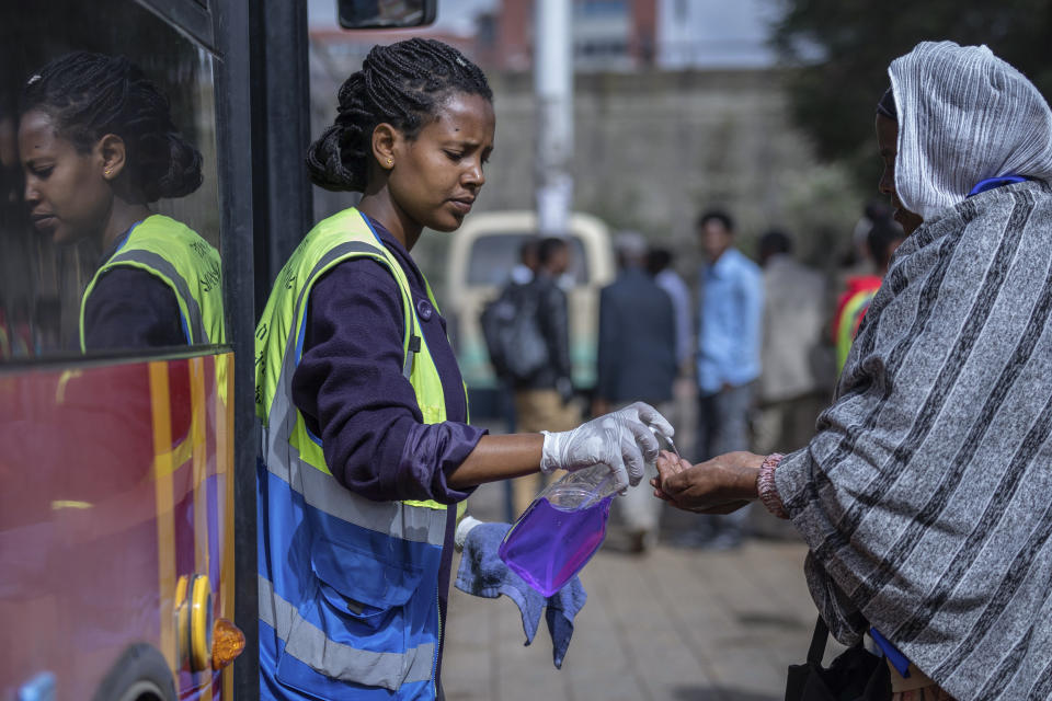 A volunteer provides hand sanitizer to passengers entering a bus as a precaution against the spread of the new coronavirus in the capital Addis Ababa, Ethiopia Wednesday, March 18, 2020. For most people, the new coronavirus causes only mild or moderate symptoms such as fever and cough and the vast majority recover in 2-6 weeks but for some, especially older adults and people with existing health issues, the virus that causes COVID-19 can result in more severe illness, including pneumonia. (AP Photo/Mulugeta Ayene)