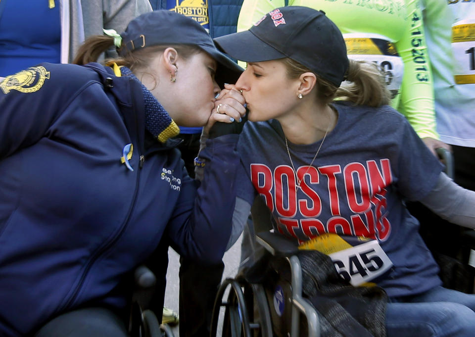 Survivors of the Boston Marathon bombings, Erika Brannock, left, and Rebekah Gregory DiMartino, embrace in their wheelchairs as they head to the finish line of the Boston Marathon Tribute Run in Boston, Saturday, April 19, 2014. (AP Photo/Elise Amendola)