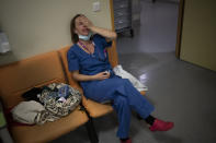 Nurse Marie-Laure Satta caresses her face during a pause in her New Year's Eve shift in the COVID-19 intensive care unit at the la Timone hospital in Marseille, southern France, Friday, Dec. 31, 2021. Paris region health authorities have instructed hospitals to cancel more non-urgent medical procedures to free up intensive-care beds for the growing influx of people gravely sick with COVID-19. (AP Photo/Daniel Cole)