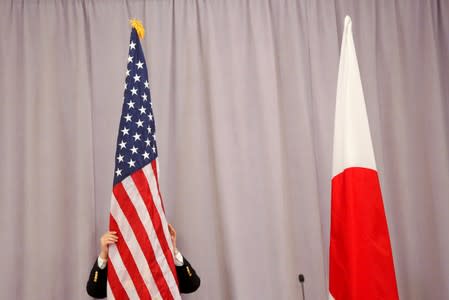 FILE PHOTO: A worker adjusts the U.S. flag before Japanese Prime Minister Shinzo Abe addresses media following a meeting with President-elect Donald Trump in Manhattan, New York, U.S.