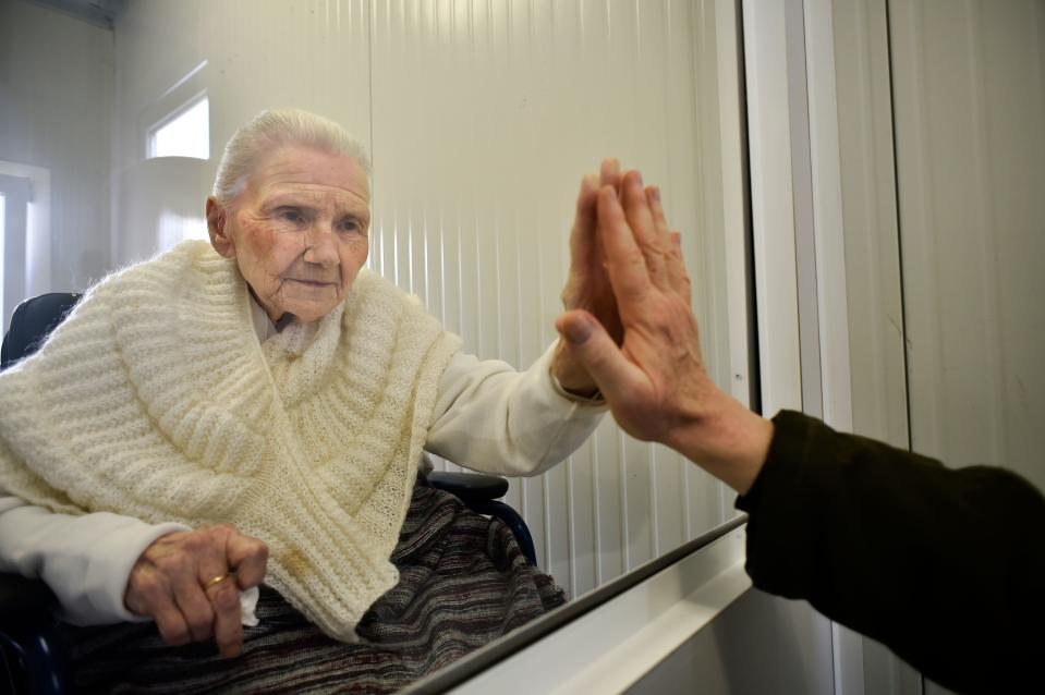 Suzanne Valette, 88, infected with COVID-19, meets her son Philippe Melard through a plexiglass lock inside the contenair at the Buissonets retirement home which has been converted into a visiting room for the relatives,  in Horion-Hozemont, a section of the municipality of Grace-Hollogne, on April 29, 2020. - Belgium is in its seventh week of confinement in the ongoing corona virus crisis. The government has announced a phased plan to attempt an exit from the lockdown situation in the country, continuing to avoid the spread of Covid-19. (Photo by JOHN THYS / AFP) (Photo by JOHN THYS/AFP via Getty Images)