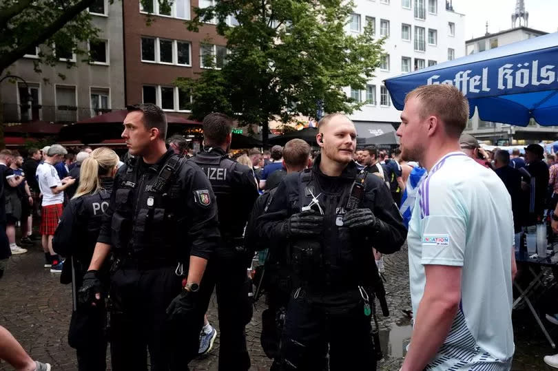 A police officer speaks to a Scotland fan at the Old Market in Cologne, Germany. -Credit:PA