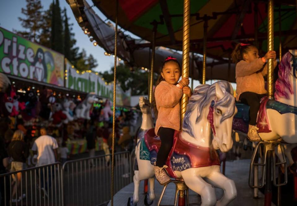 Jayleen Méndez, de cinco años, a la izquierda, y su hermana Jaclyn Méndez, de tres, de Sacramento, montan en el carrusel de la Feria del Condado de Sacramento en Cal Expo en 2023.