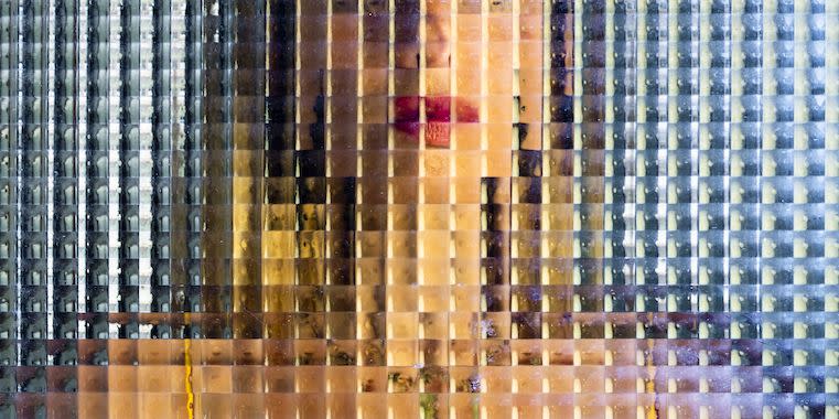 woman in a yellow vest behind distorted glass giving the impression she's been pixelated or censored