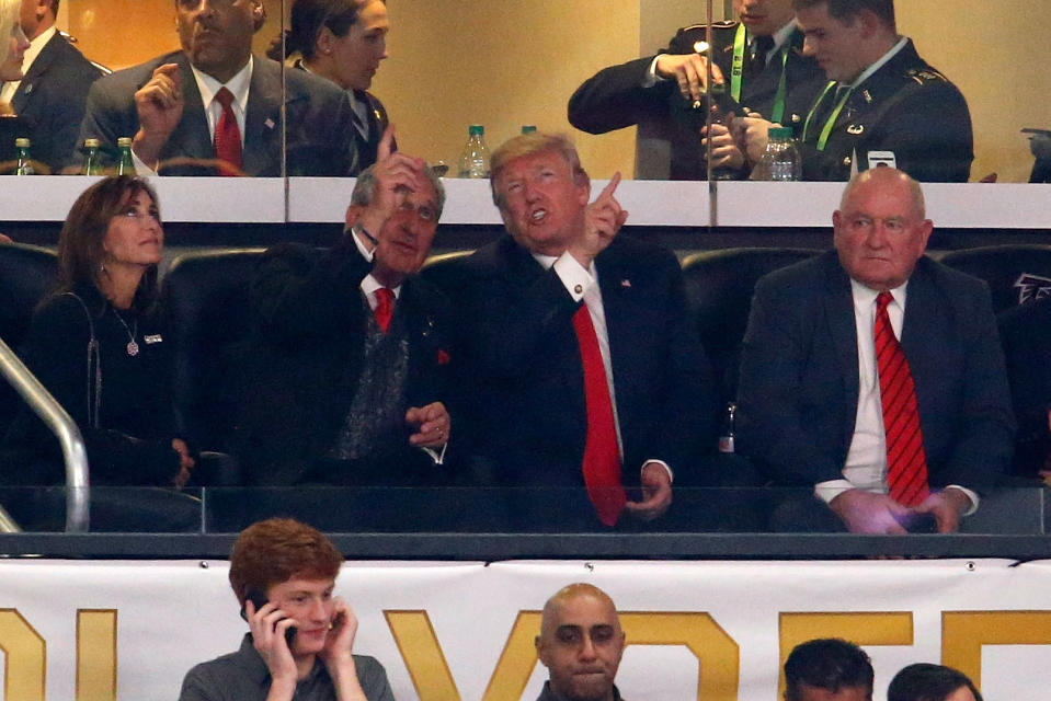 President Donald Trump takes in the college football national championship while chatting with Atlanta Falcons owner Arthur Blank (L) in January. (Getty Images)