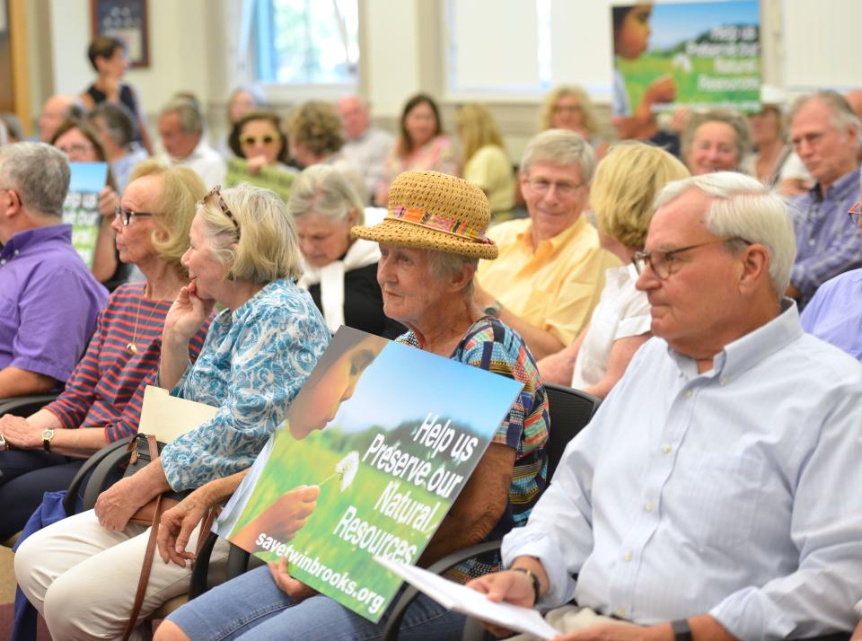 Betsy Broecker of Hyannis holds a sign Thursday in Barnstable Town Hall in protest of housing planned at the Twin Brooks golf course property, ahead of a Town Council meeting. Council members considered but did not approve a rule change to ease the path for developers to obtain some zoning exceptions.