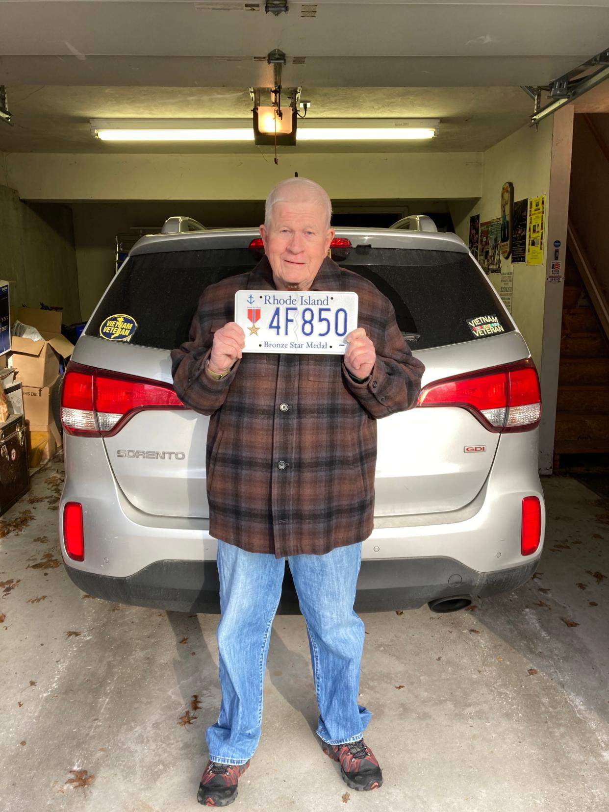 Standing in the driveway of his Tiverton home, Vietnam combat veteran Ed Campbell holds his Bronze Star plate starting with “4F.” In Selective Service jargon, 4F means “unfit for military service.”