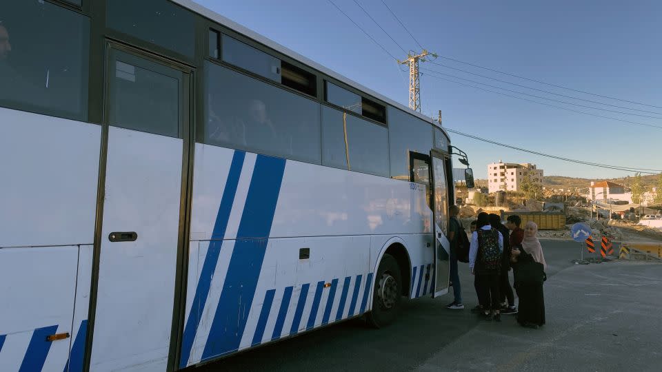 A bus taking West Bank residents through an Israeli checkpoint and into Jerusalem stops to pick up passengers waiting by the side of the road, on Monday, November 6. - Ivana Kottasova/CNN