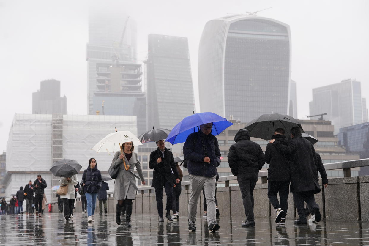 People walk in the rain over London Bridge in central London after rain fell for much on the day on Tuesday. (PA)