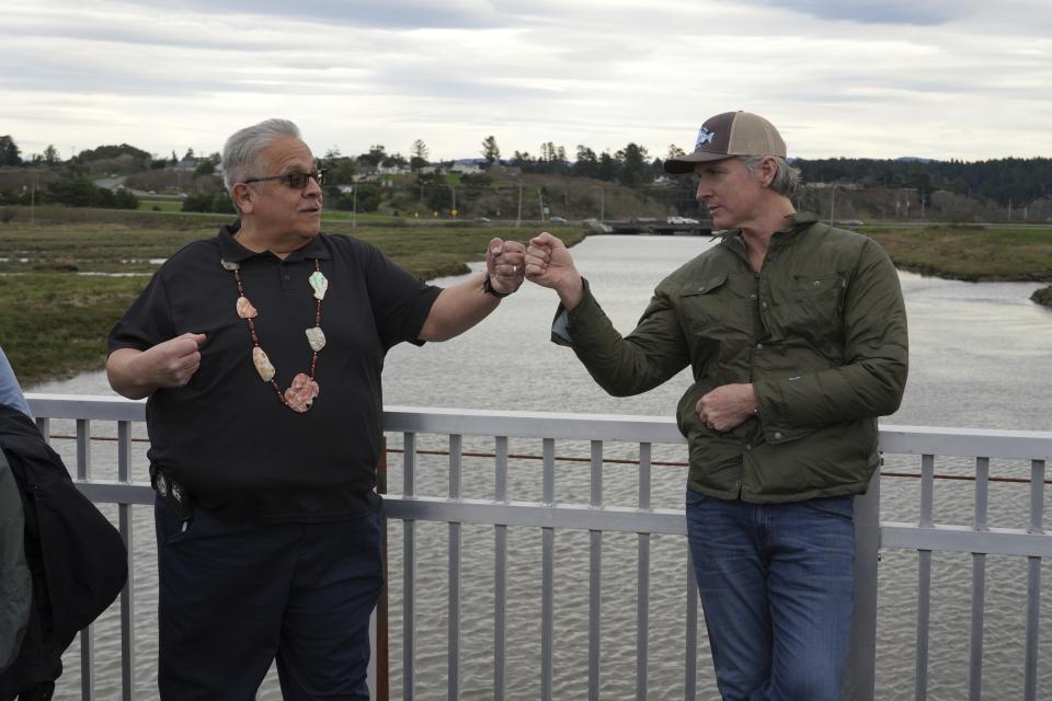California Gov. Gavin Newsom fist-bumps Wiyot Tribal Chair Ted Hernandez at the Elk River where they were touring a salmon restoration project in Eureka, Calif., Monday, Jan. 29, 2024. (AP Photo/Terry Chea)