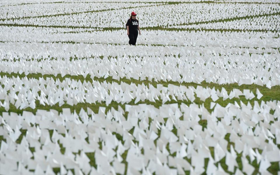 A woman walks through a field of white flags on the Mall near the Washington Monument in Washington, DC on September 16
