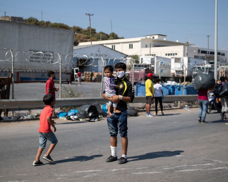 A man holds a child at the area where refugees and migrants from the destroyed Moria camp are sheltered, near a new temporary camp, on the island of Lesbos