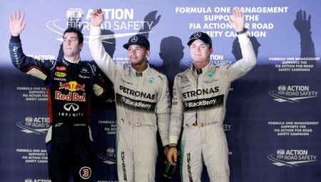 Mercedes Formula One driver Lewis Hamilton of Britain waves to fans, flanked by team mate Nico Rosberg (R) of Germany and Red Bull Formula One driver Daniel Ricciardo (L) of Australia, after he won the pole position during the qualifying session of Singapore F1 Grand Prix at the Marina Bay street circuit in Singapore September 20, 2014. REUTERS/Tim Chong