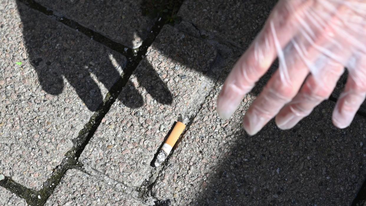 Ein Mann sammelt eine Zigarettenstummel vom Boden auf. Foto: Patrick Seeger