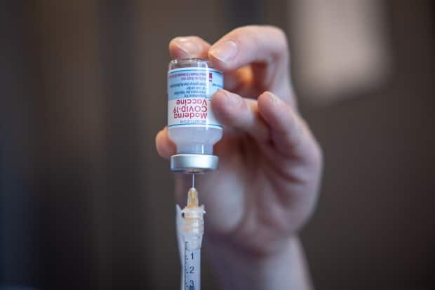 A health-care worker dispenses Moderna COVID-19 vaccine from a vial. Each vial has 14 doses, and once opened, the entire bottle has to be used within 24 hours (Robert Short/CBC - image credit)