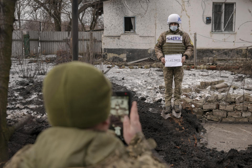 Members of the Joint Centre for Control and Coordination on ceasefire of the demarcation line, or JCCC, take forensic photos of a crater and damage to a house from artillery shell that landed in Vrubivka, one of the at least eight that hit the village today, according to local officials, in the Luhansk region, eastern Ukraine, Thursday, Feb. 17, 2022. U.S. President Joe Biden warned that Russia could still invade Ukraine within days and Russia expelled the No. 2 diplomat at the U.S. Embassy in Moscow, as tensions flared anew in the worst East-West standoff in decades. (AP Photo/Vadim Ghirda)