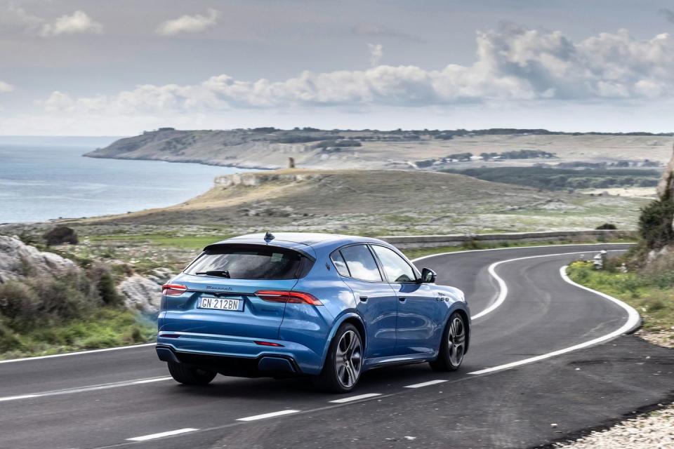 a blue car on a road by the water