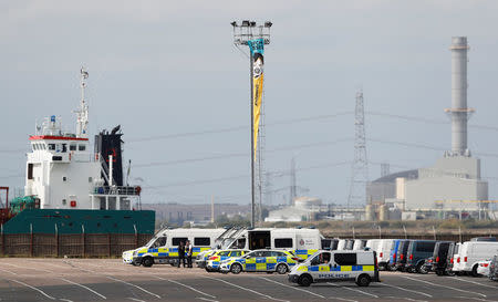 Police vehicles are parked as Greenpeace activists unfurl a banner from a lighting tower after activists entered the vehicle park in a protest against Volkswagen diesel vehicles at the port of Sheerness, Britain, September 21, 2017. REUTERS/Peter Nicholls