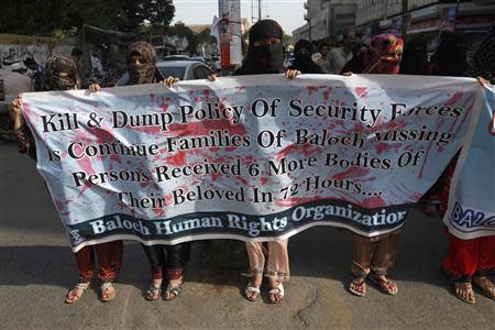 Members of the Baloch Human Rights Organization hold banners while protesting outside Karachi Press Club August 21, 2013. REUTERS/Stringer