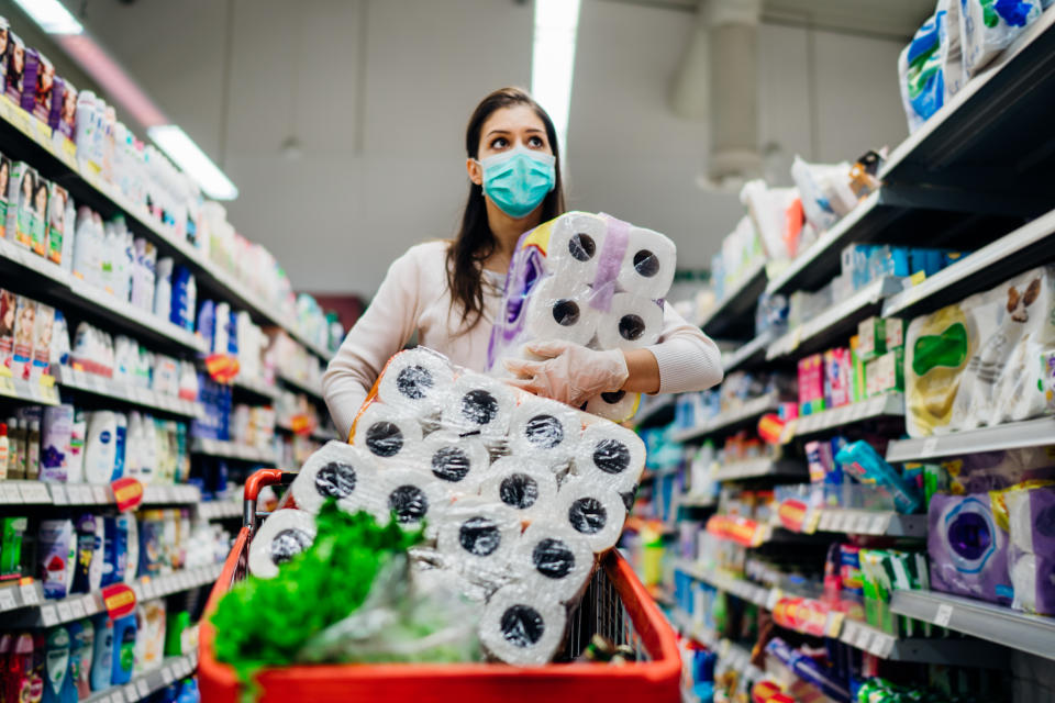 Toilette paper shortage.Woman with hygienic mask shopping for toilette paper supplies due to panic buying and product hoarding during virus epidemic outbreak.Hygiene products deficiency