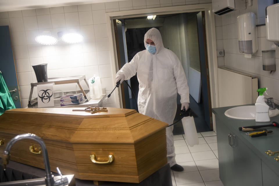 A worker, wearing a full protective equipment, disinfects the casket of someone who died of coronavirus COVID-19 at the Fontaine funeral home in Charleroi, Belgium, Tuesday, Nov. 17, 2020. One of the hardest-hit countries in Europe, Belgium has reported more than 535,000 confirmed virus cases and more than 14,400 deaths linked to the coronavirus. (AP Photo/Francisco Seco)