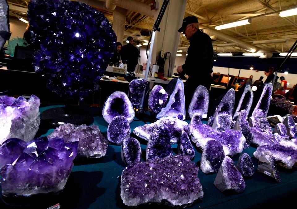 Amethyst glitters in the foreground as Steve Hilliard of Stones & Old Bones turns to bag an item for a customer.