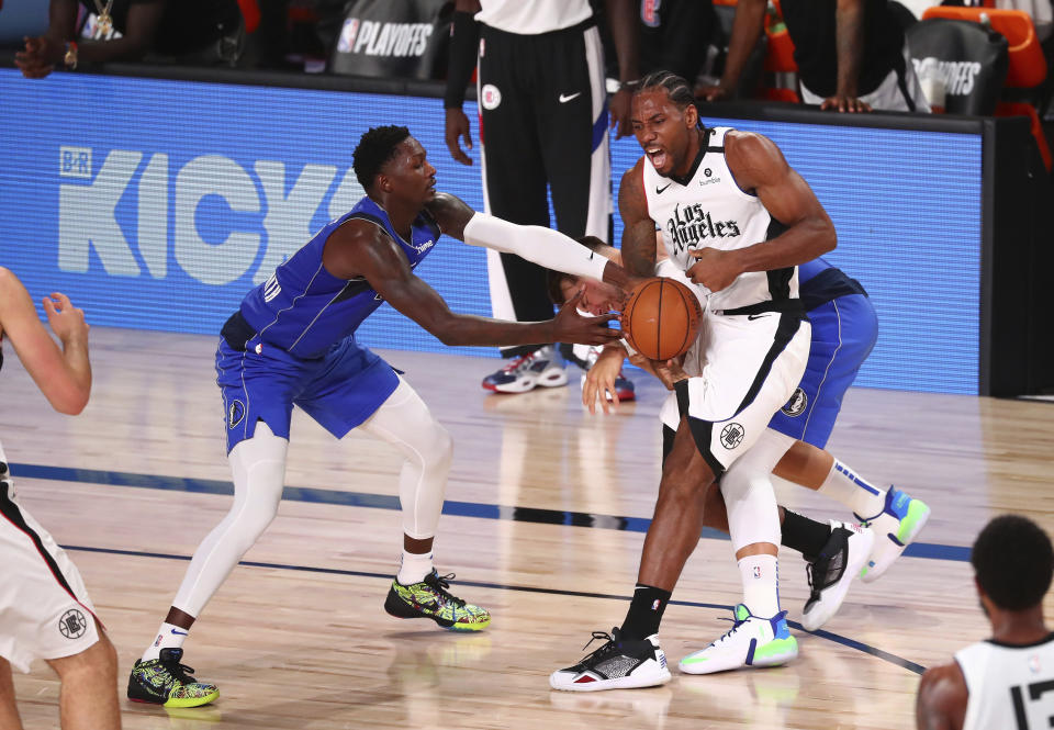 Dallas Mavericks forward Dorian Finney-Smith, left, and guard Luka Doncic steal the ball from Los Angeles Clippers forward Kawhi Leonard during the second half of Game 5 of an NBA basketball first-round playoff series, Tuesday, Aug. 25, 2020, in Lake Buena Vista, Fla. (Kim Klement/Pool Photo via AP)