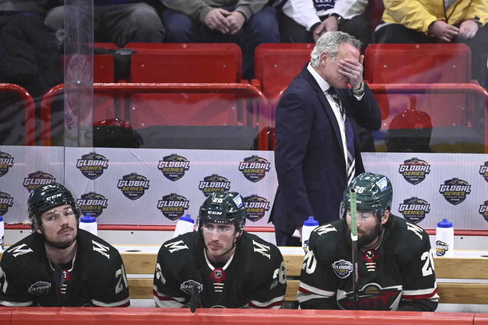 Minnesota's head coach Dean Evason, standing, reacts as players Brandon Duhaime, left, Connor Dewar and Pat Maroon, right, look on during the NHL Global Series Sweden ice hockey match between Toronto Maple Leafs and Minnesota Wild at Avicii Arena in Stockholm, Sweden, Sunday Nov. 19, 2023. (Claudio Bresciani/TT via AP)