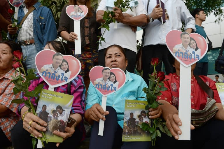 Supporters hold flowers and heart-shaped cut-outs carrying pictures of deposed former Thai premiers Yingluck Shinawatra (R) and her brother Thaksin, outside the supreme court in Bangkok, on January 15, 2016