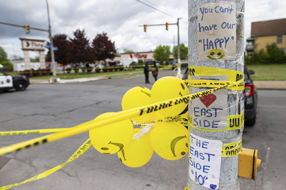 Signs, balloons and police tape are wrapped around a pole across from Tops Friendly Market on Tuesday, May 17, 2022, in Buffalo, N.Y. Tops, the Buffalo grocery store where 10 Black people were killed in a racist shooting rampage, was more than a place to buy groceries. As the only supermarket for miles, residents say the store was a sort of community hub where they chatted with neighbors and caught up on each other’s lives. (AP Photo/Joshua Bessex)