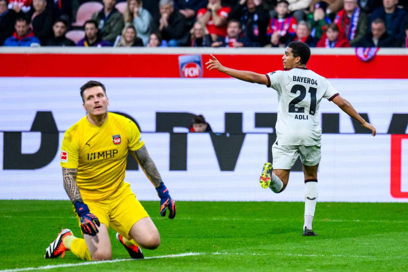 Leverkusen's Amine Adli (R) celebrates scoring his side's second goal while Heidenheim goalkeeper Kevin Mueller reacts in dejection during the German Bundesliga soccer match between 1. FC Heidenheim and Bayer Leverkusen at the Voith-Arena. Tom Weller/dpa