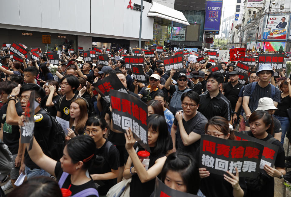 Protesters carrying signs reading "Demand accountability for shooting/Withdraw charges!" march through the streets against an extradition bill on Sunday, June 16, 2019, in Hong Kong. Tens of thousands of Hong Kong residents, mostly in black, have jammed the city's streets Sunday to protest the government's handling of a proposed extradition bill. (AP Photo/Vincent Yu)