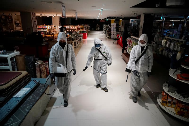 Employees from a disinfection service company sanitize at a department store in Seoul